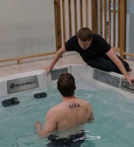 John Buffam Kinesiologist coaching client doing Aquatic Rehab in HydroWorx Pool in front of motion capture camera and TV at Pure Movement Physiotherapy & Aquatic Rehab Stittsville Kanata Ontario