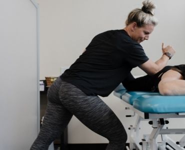 Shawna Emmott Owner & Physiotherapist at Pure Movement Physiotherapy & Aquatic Rehab in Stittsville Ontario, with elbow in patient's back practicing physio